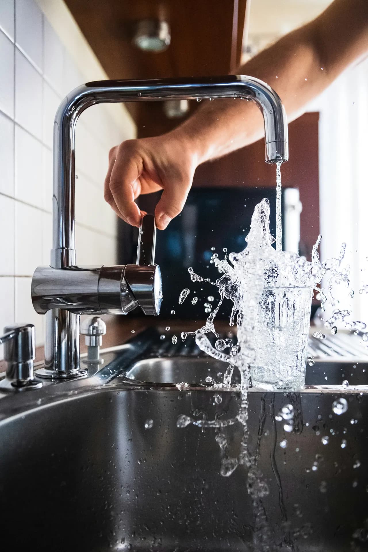 Water running from a kitchen mixer faucet into a glass